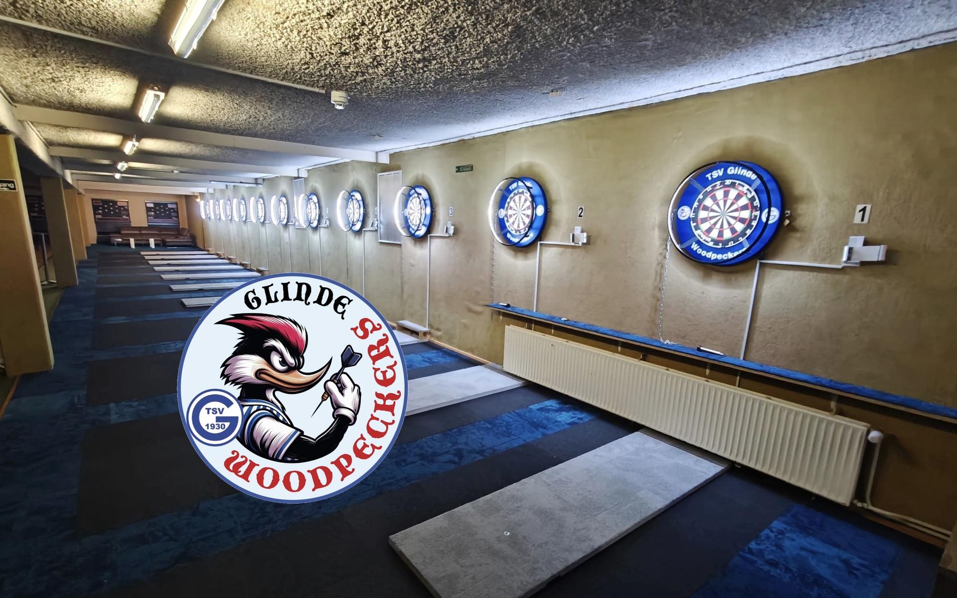 Blick auf einen Dartsaal mit mehreren beleuchteten Dartscheiben und einem Logo der Glinde Woodpeckers im Vordergrund.