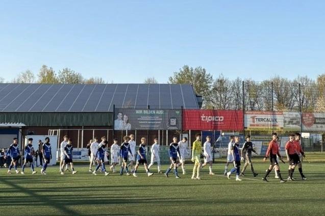 Spieler in blauen und wei&szlig;en Trikots betreten das Fu&szlig;ballfeld, begleitet von Schiedsrichtern in Schwarz.