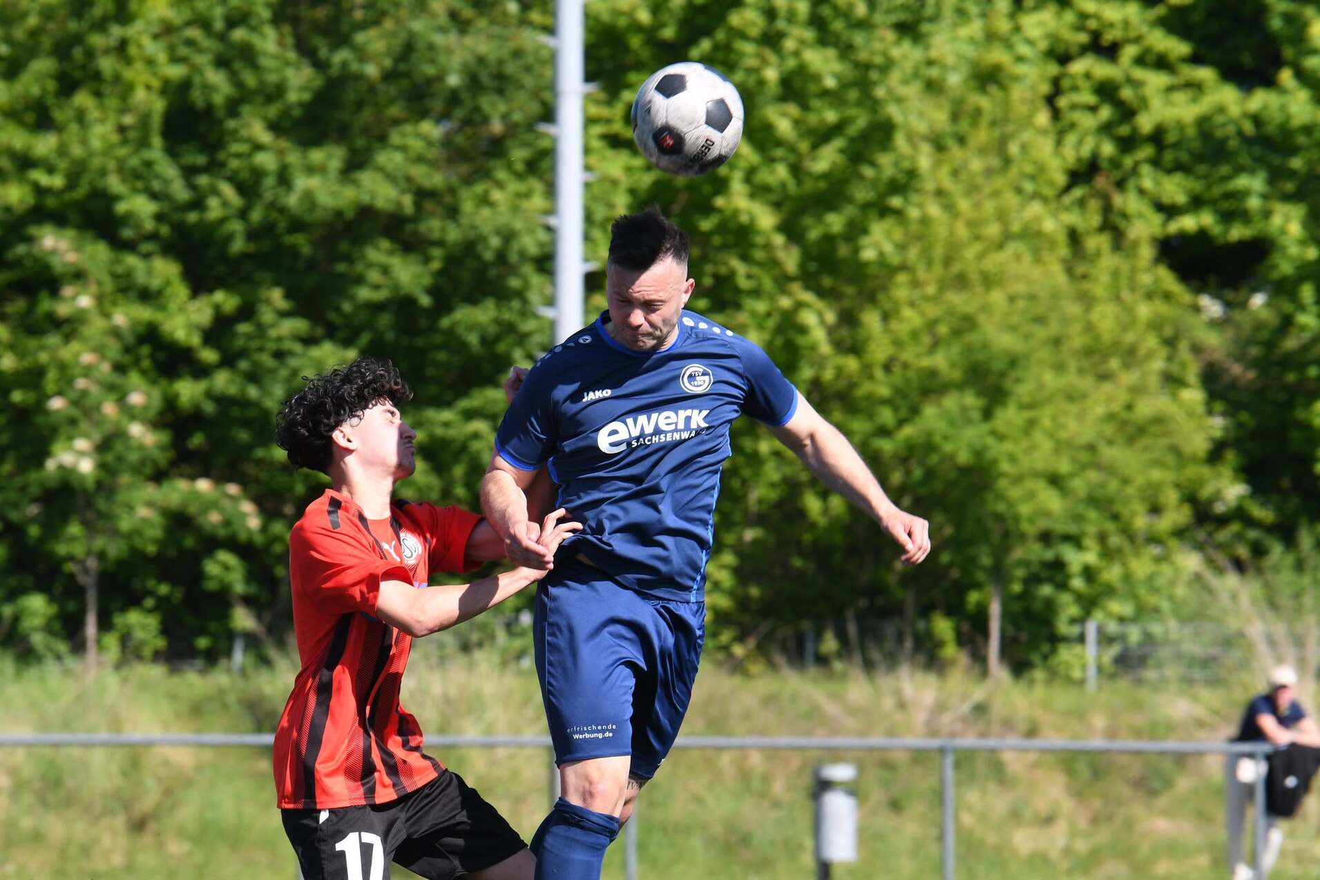 Zwei Fußballspieler in Aktion: Ein Spieler springt zum Kopfball, während der andere ihn verteidigt.