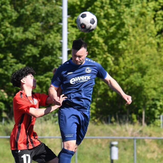 Zwei Fußballspieler in Aktion: Ein Spieler springt zum Kopfball, während der andere ihn verteidigt.