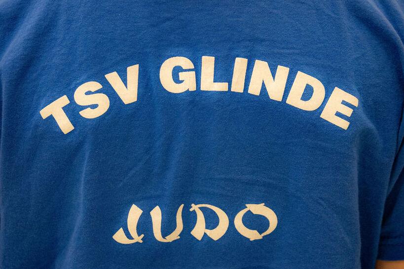 Rückenansicht eines blauen T-Shirts mit dem Aufdruck „TSV GLINDE JUDO“ in weißen Buchstaben.