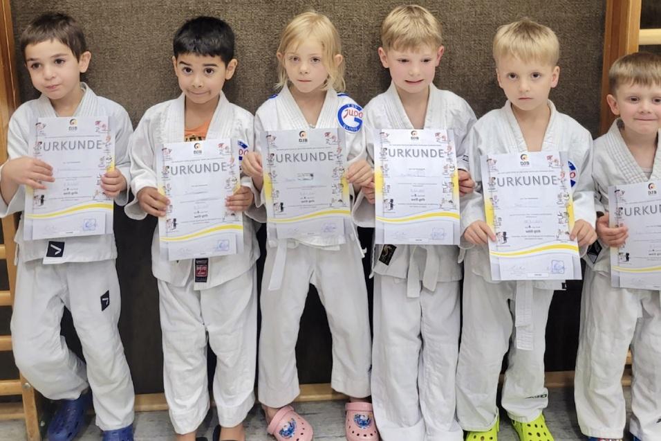 Sechs Kinder in wei&szlig;en Karateanz&uuml;gen halten stolz ihre Urkunden in der Hand.