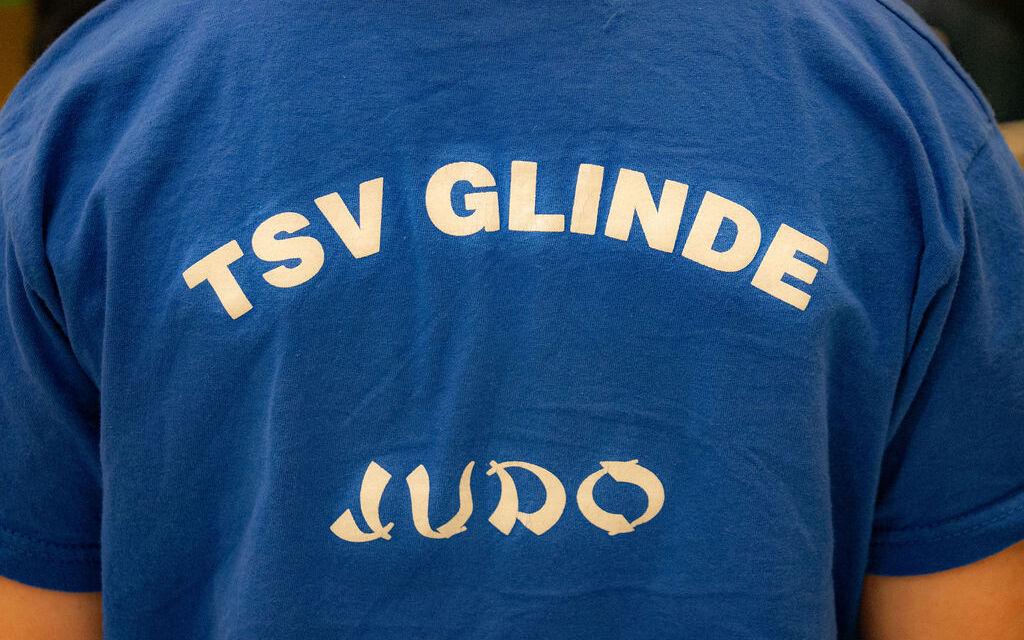 Rückenansicht eines blauen T-Shirts mit dem Aufdruck „TSV GLINDE JUDO“ in weißen Buchstaben.