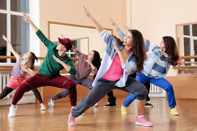 Gruppe von fünf Tänzern in einem Tanzstudio, die synchron eine dynamische Pose einnehmen.