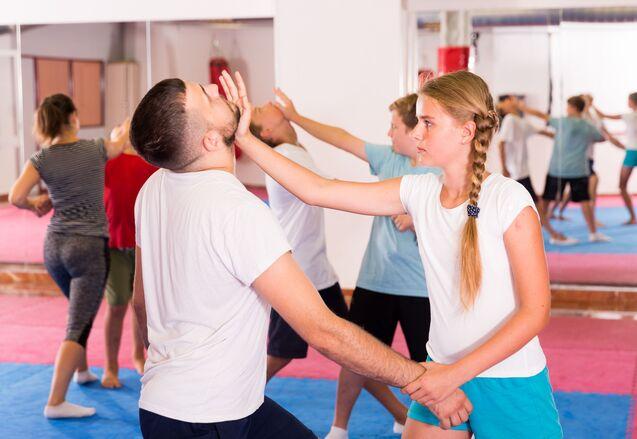 Trainingseinheit in einer Kampfsporthalle mit mehreren Personen, die Techniken im Partnertraining ausführen.