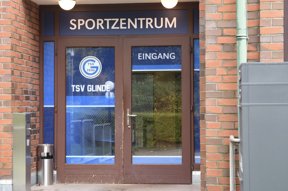 Eingangst&uuml;r eines Sportzentrums mit Aufschrift &bdquo;SPORTZENTRUM&ldquo; und &bdquo;TSV GLINDE&ldquo; in blauer Schrift.