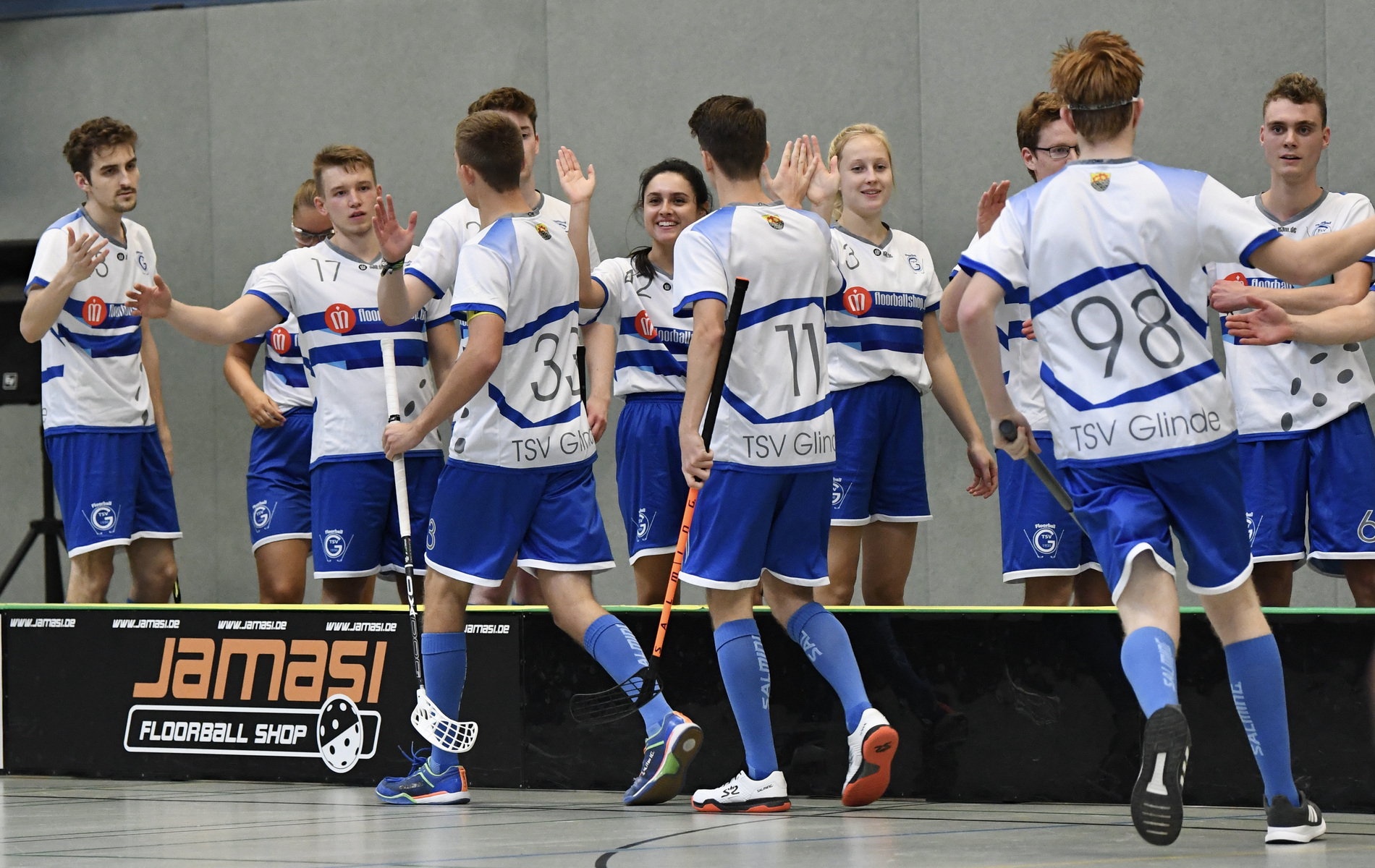 Gruppenszene von Spielern des TSV Glinde, die einander nach einem Spiel auf einer Sporthalle begr&uuml;&szlig;en und feiern.