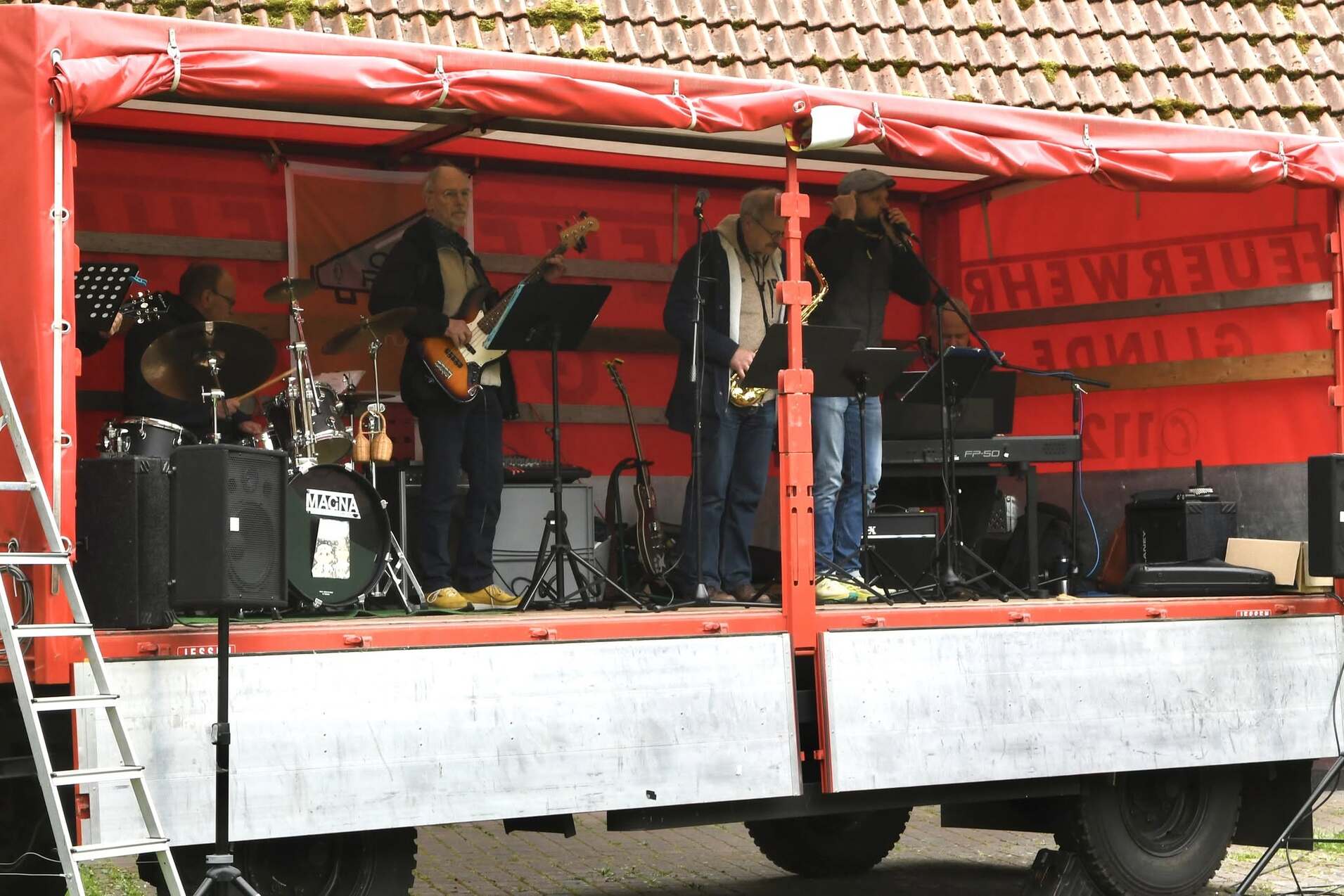 Live-Band auf einem mobilen Bühnenanhänger mit Instrumenten und Musikern in einer festlichen Umgebung.