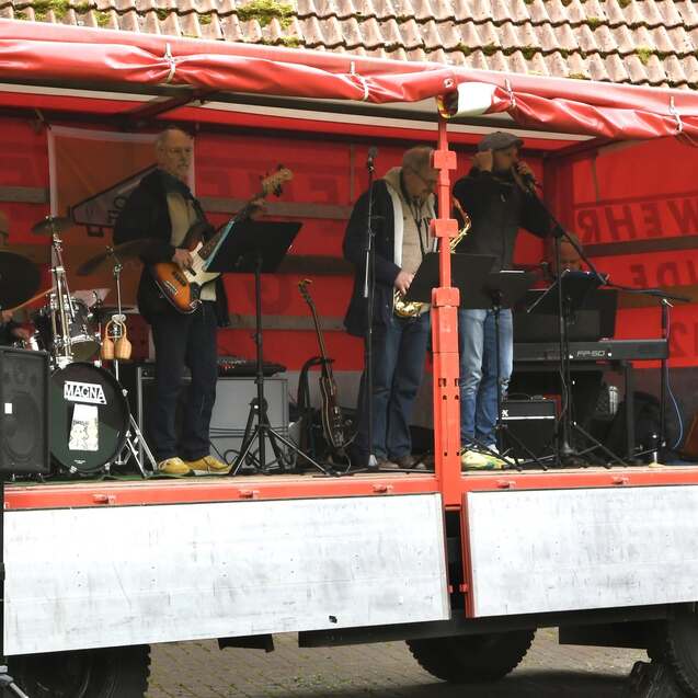 Live-Band auf einem mobilen Bühnenanhänger mit Instrumenten und Musikern in einer festlichen Umgebung.