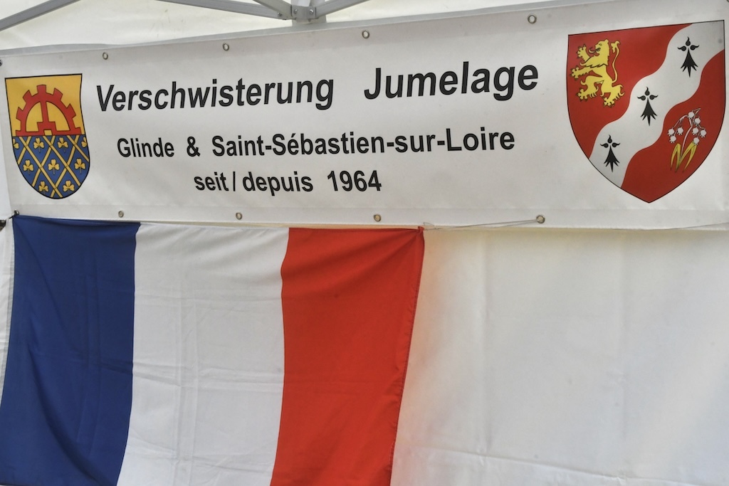 Banner mit der Aufschrift &bdquo;Verschwisterung Jumelage Glinde & Saint-S&eacute;bastien-sur-Loire seit 1964&ldquo; und Flaggen.